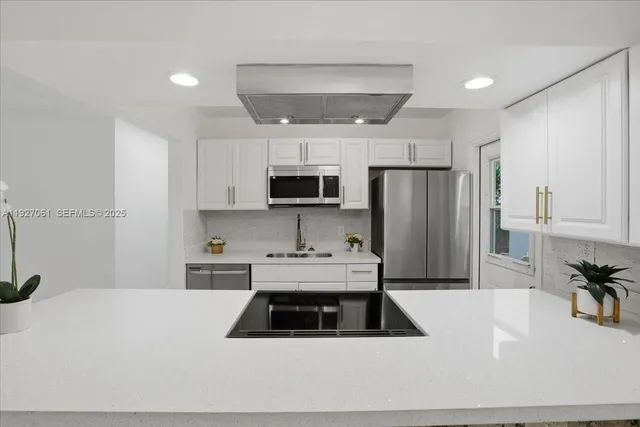 a kitchen with a sink a stove a microwave a refrigerator a counter top space and cabinets