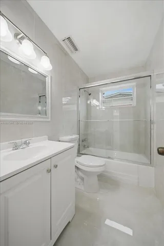 a bathroom with a shower sink vanity mirror and toilet
