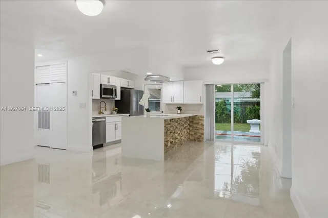 a large white kitchen with cabinets and a large window