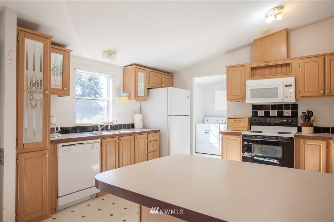5390 East Harbor Road Freeland, WA 98249 - Photo 4 of 17 a kitchen with granite countertop a refrigerator stove top oven and sink
