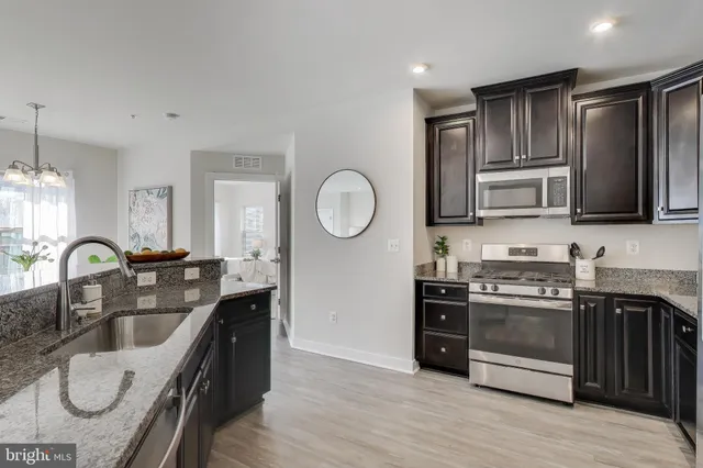 a kitchen with stainless steel appliances granite countertop a sink a stove a refrigerator cabinets and a window