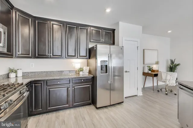 a kitchen with stainless steel appliances granite countertop a refrigerator and a stove top oven