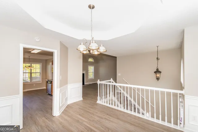 a view of a hallway with wooden floor and a chandelier