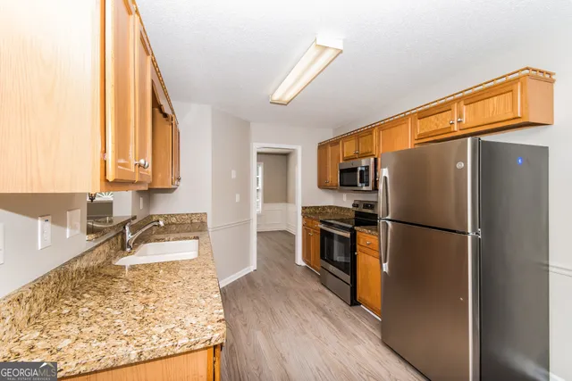 a kitchen with granite countertop a refrigerator and a sink