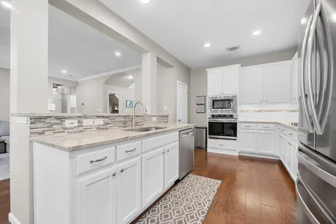 a kitchen with stainless steel appliances granite countertop a stove top oven a sink and white cabinets