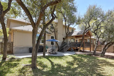 a view of a house with large trees and a yard