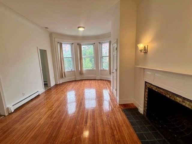 591 Beacon Street, Unit 3 Boston, MA 02215 - Photo 6 of 9 a view of empty room with wooden floor and fireplace