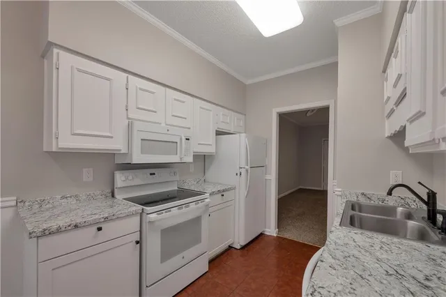 a kitchen with granite countertop white cabinets and white appliances