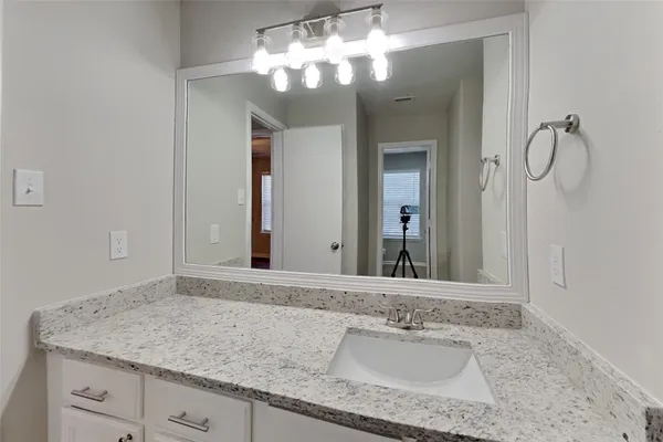 a bathroom with a granite countertop sink and a mirror
