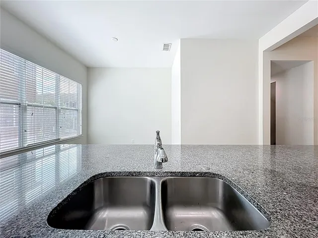 a view of an empty room with window and chandelier fan