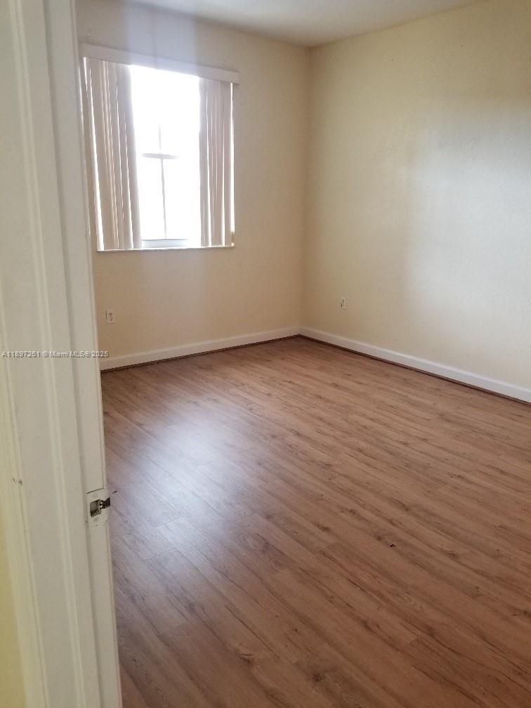 1663 Southeast 27th Drive, Unit 202 Homestead, FL 33035 - Photo 5 of 16 an empty room with wooden floor and windows