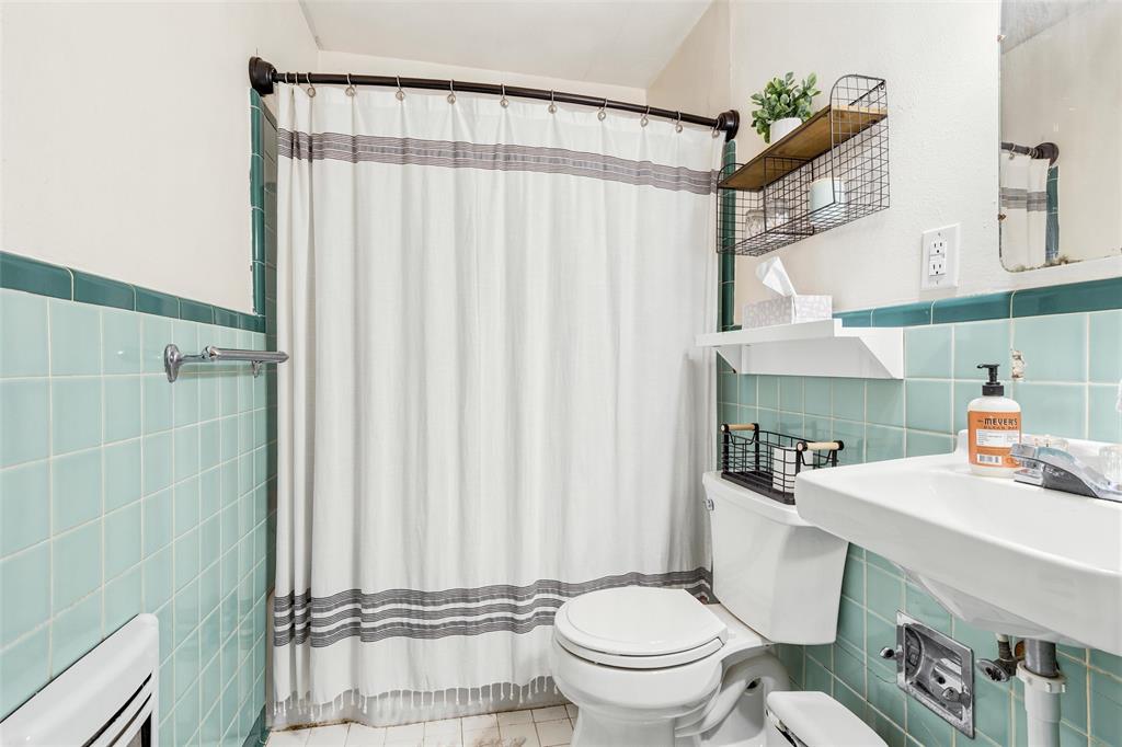 3012 Mitchell Avenue Waco, TX 76708 - Photo 13 of 18 Bathroom featuring light green square tile walls, a white wall-mounted sink, and a white toilet
