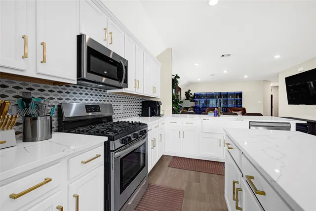 a kitchen with stainless steel appliances granite countertop a stove top oven a sink a microwave and a refrigerator