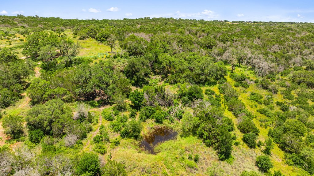 1101 Crider Road Marble Falls, TX 78654 - Photo 4 of 37 Vast natural terrain features dense tree coverage and a tranquil pond, offering serene undeveloped acreage.