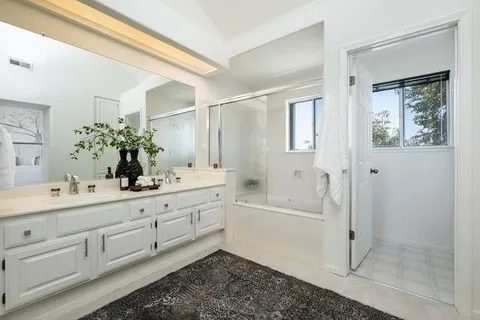 a bathroom with a double vanity sink a toilet and shower