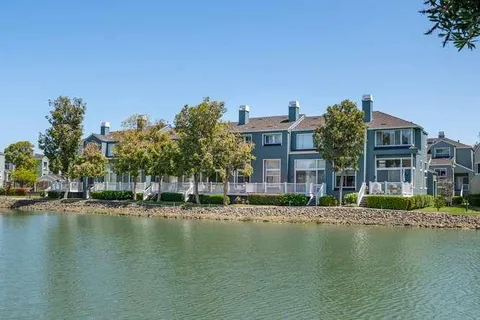 a front view of a building with lake view and trees around