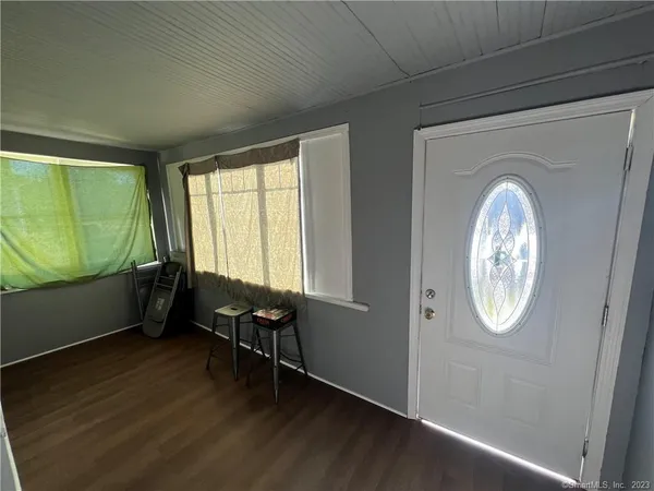an empty room with wooden floor mirror and windows