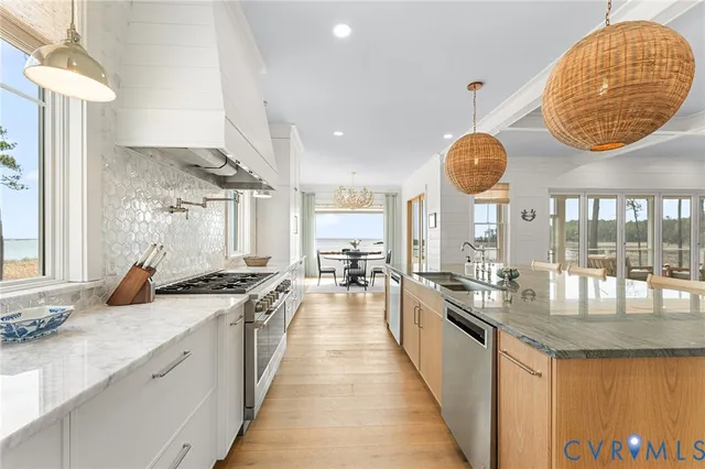 a large kitchen with kitchen island a large counter space a sink stainless steel appliances and a chandelier