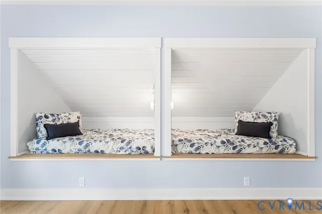 a view of a living room with a bed and wooden floor