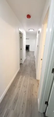 a view of a hallway with wooden floor and a cabinet