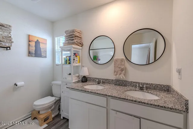 a bathroom with a granite countertop sink a toilet and a shower