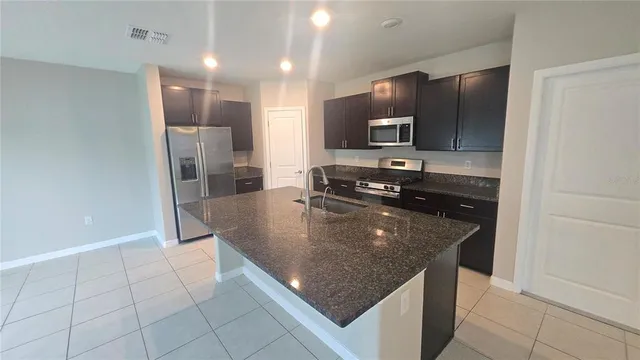a kitchen with kitchen island granite countertop a sink a stove and refrigerator