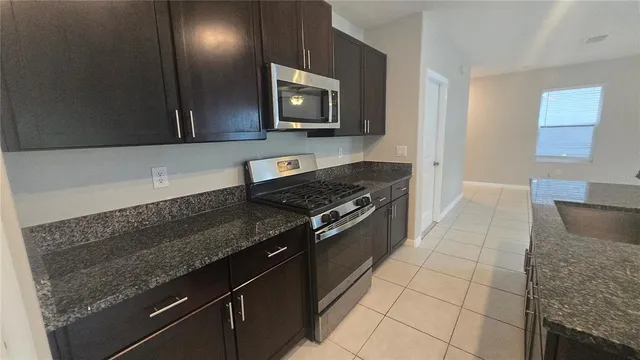 a kitchen with granite countertop a stove and a microwave