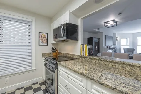 a view of a kitchen with kitchen island granite countertop a sink and a stove top oven