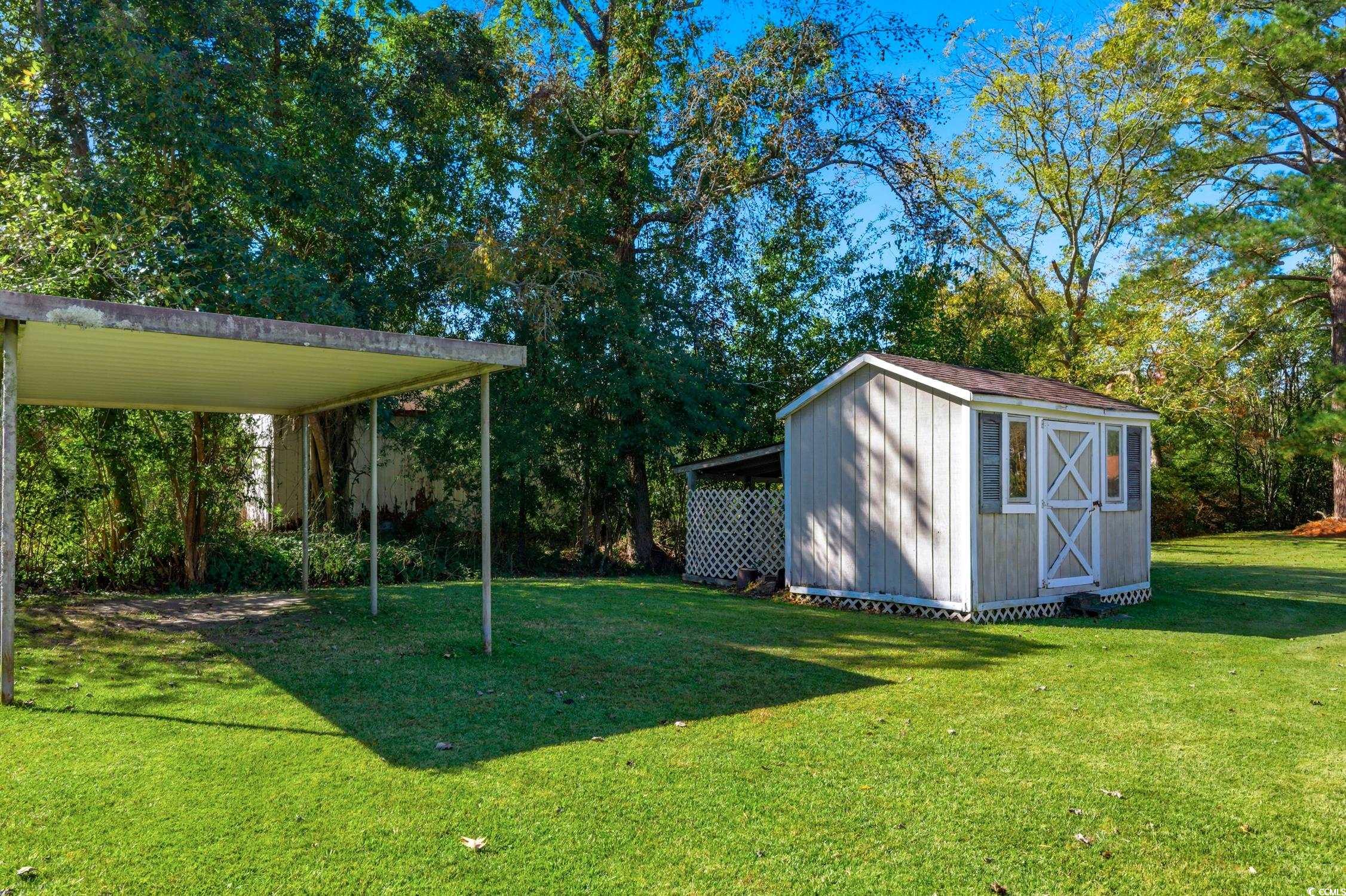 1605 Sessions Street Conway, SC 29526 - Photo 8 of 20 View of grassy yard featuring a storage unit, view of scattered trees, and a carport
