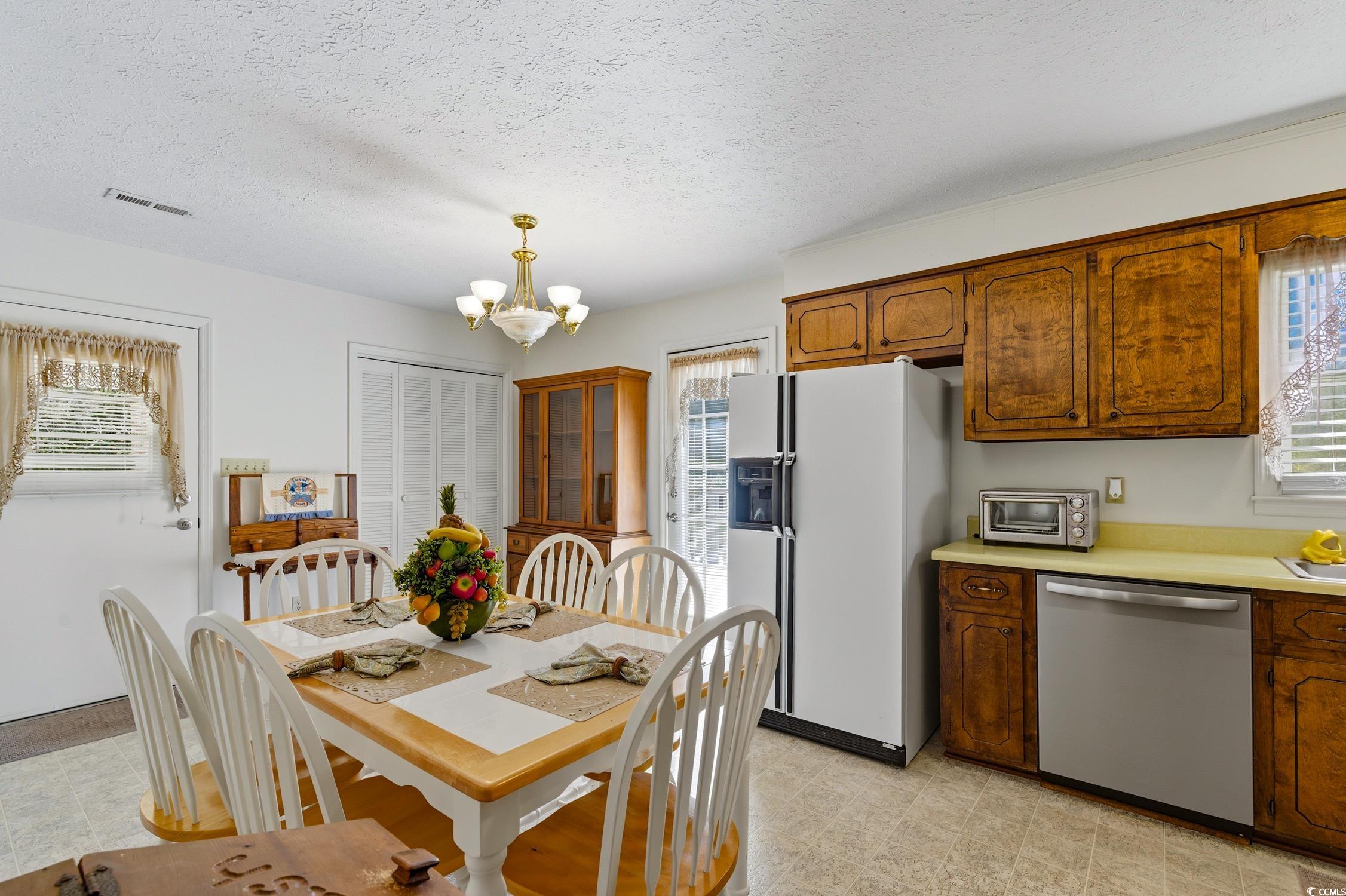 1605 Sessions Street Conway, SC 29526 - Photo 10 of 20 Kitchen with a textured ceiling, white fridge with ice dispenser, stainless steel dishwasher, light countertops, and brown cabinetry