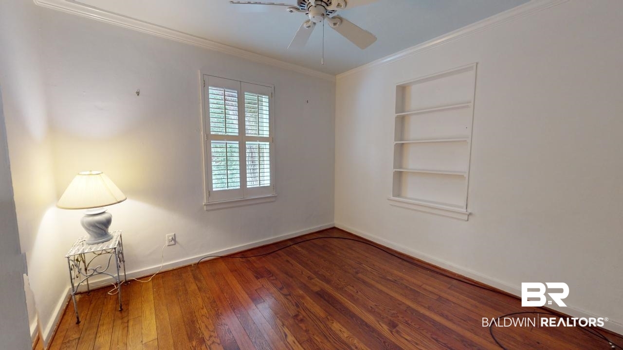 48 Hathaway Road West Mobile, AL 36608 - Photo 22 of 40 Unfurnished room with built in features, ceiling fan, ornamental molding, and hardwood / wood-style flooring