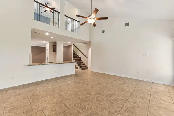a view of an empty room with chandelier fan
