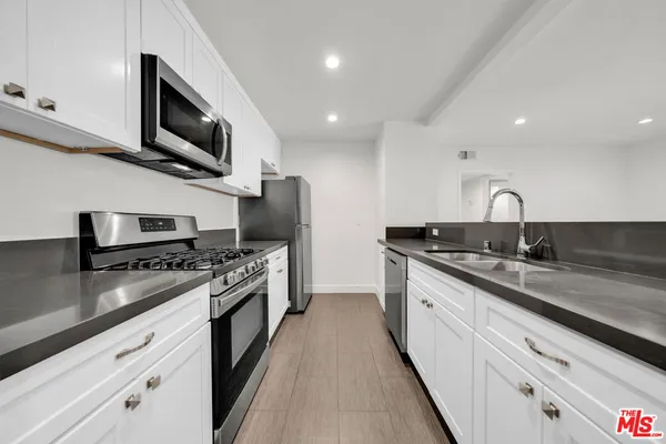 a kitchen with stainless steel appliances granite countertop a sink a stove top oven a counter space and cabinets