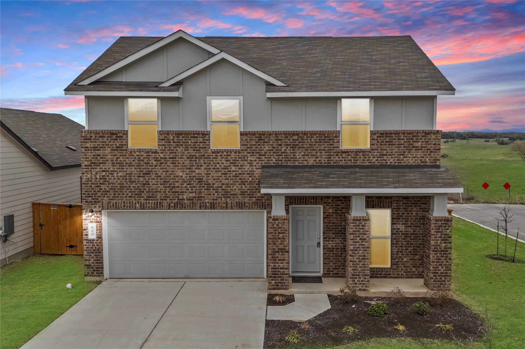 View of front of house featuring an attached garage, brick siding, a front lawn, driveway, and a shingled roof