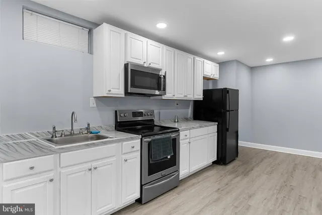 a kitchen with a sink a stove a microwave and wooden floor
