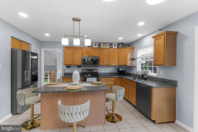 a kitchen with granite countertop a sink a stove top oven a dining table and chairs