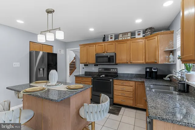 a kitchen with stainless steel appliances granite countertop a stove a sink a microwave a refrigerator and cabinets