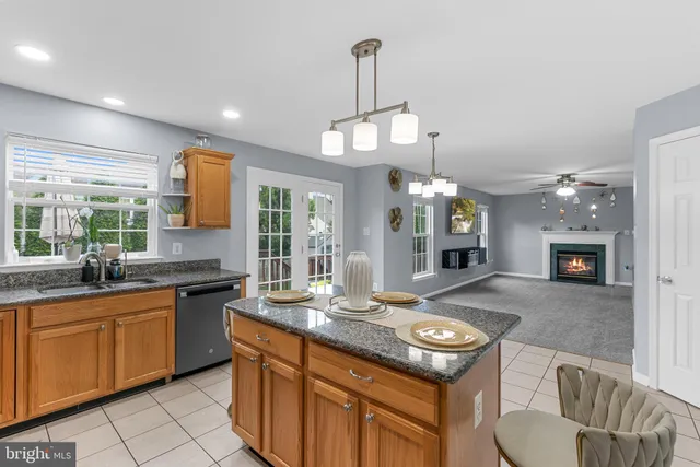 a kitchen with kitchen island granite countertop a stove a sink a dining table and chairs with wooden floor