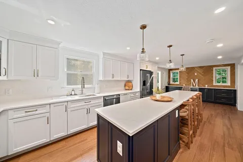 a kitchen with a stove a sink dishwasher a kitchen island with wooden cabinets and floor