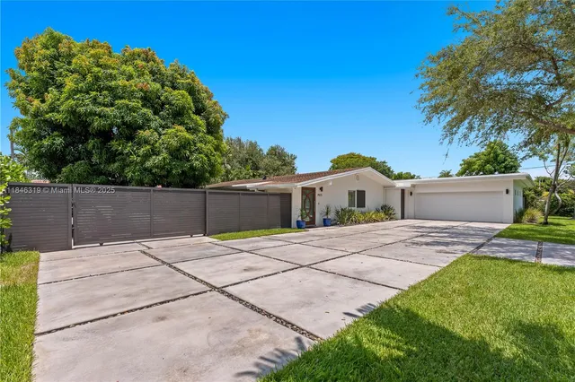 a backyard of a house with table and chairs plants and large trees