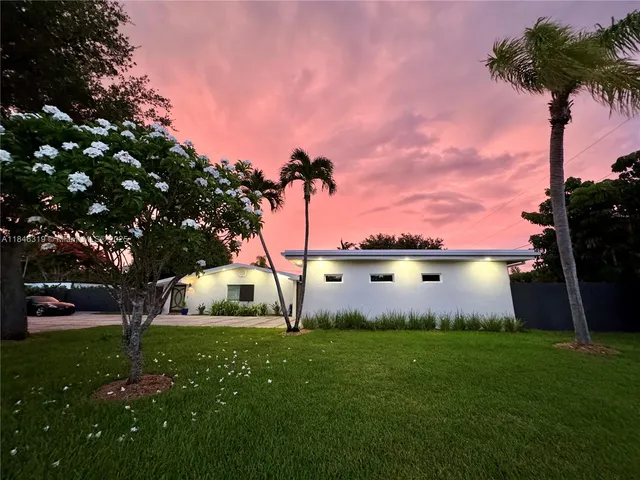 a front view of a house with garden and trees