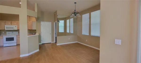 a view of a kitchen with refrigerator and wooden floor