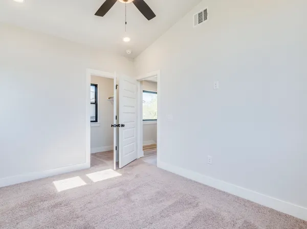 an empty room with chandelier fan and closet