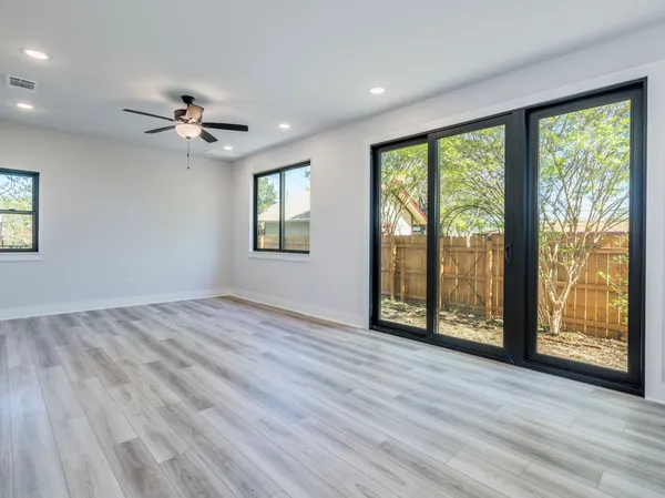 a view of an empty room with a window and wooden floor