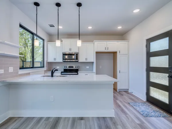 a large kitchen with stainless steel appliances a large counter top a stove a sink and a window