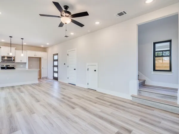 a view of a livingroom with a ceiling fan wooden floor and a ceiling fan