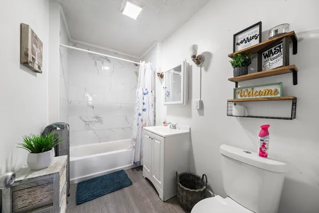 a view of a room with wooden floor kitchen ceiling fan and windows