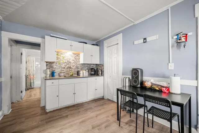 a kitchen with granite countertop white cabinets and stove with wooden floor