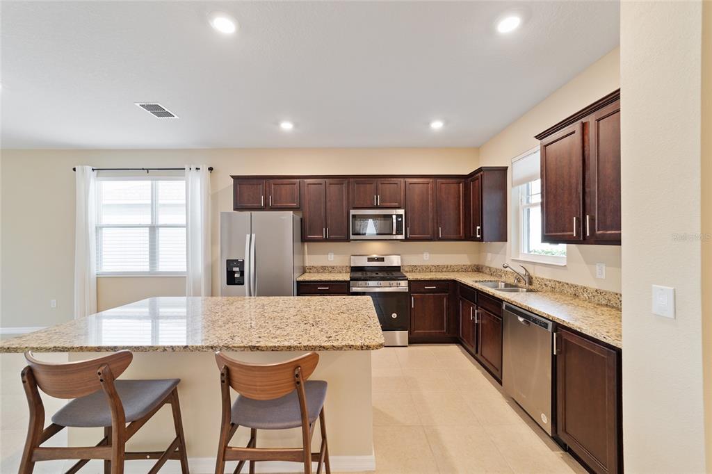 9776 Southwest 100th Avenue Ocala, FL 34481 - Photo 24 of 52 a kitchen with stainless steel appliances granite countertop a stove top oven a sink dishwasher and a refrigerator