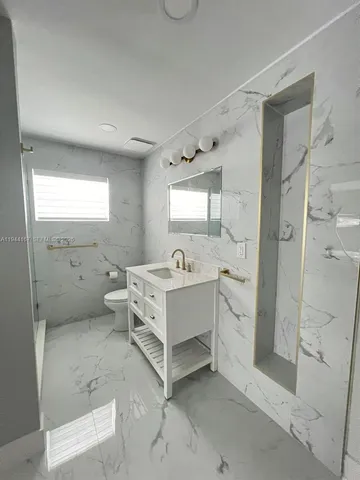 a bathroom with a double vanity sink toilet mirror and shower